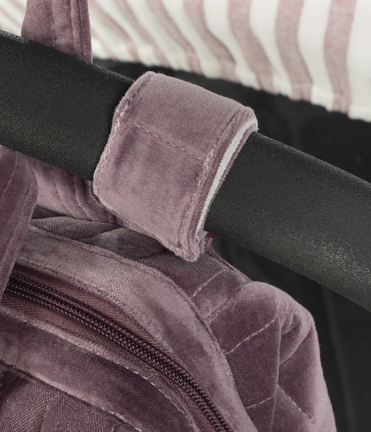 Mochila de maternidade Cherry Velvet da Pasito a Pasito pendurada no carrinho.