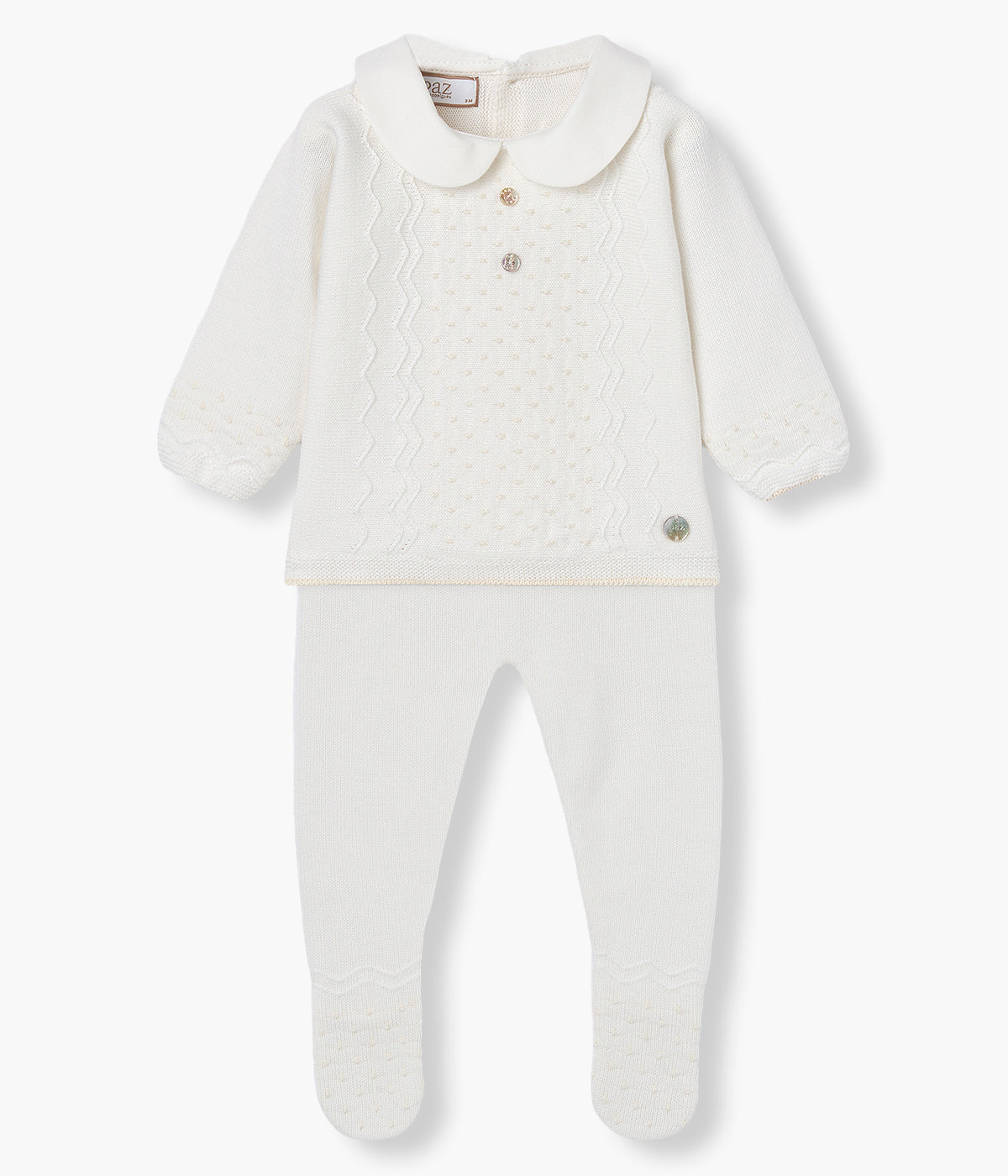 Vista de frente do conjunto de 2 peças em malha de algodão pérola da Paz Rodríguez para bebé e recém-nascido(a). Camisola com gola redonda cortada, detalhes com relevo e botões madrepérola decorativos. Calças com pés com detalhes a combinar com a camisola.