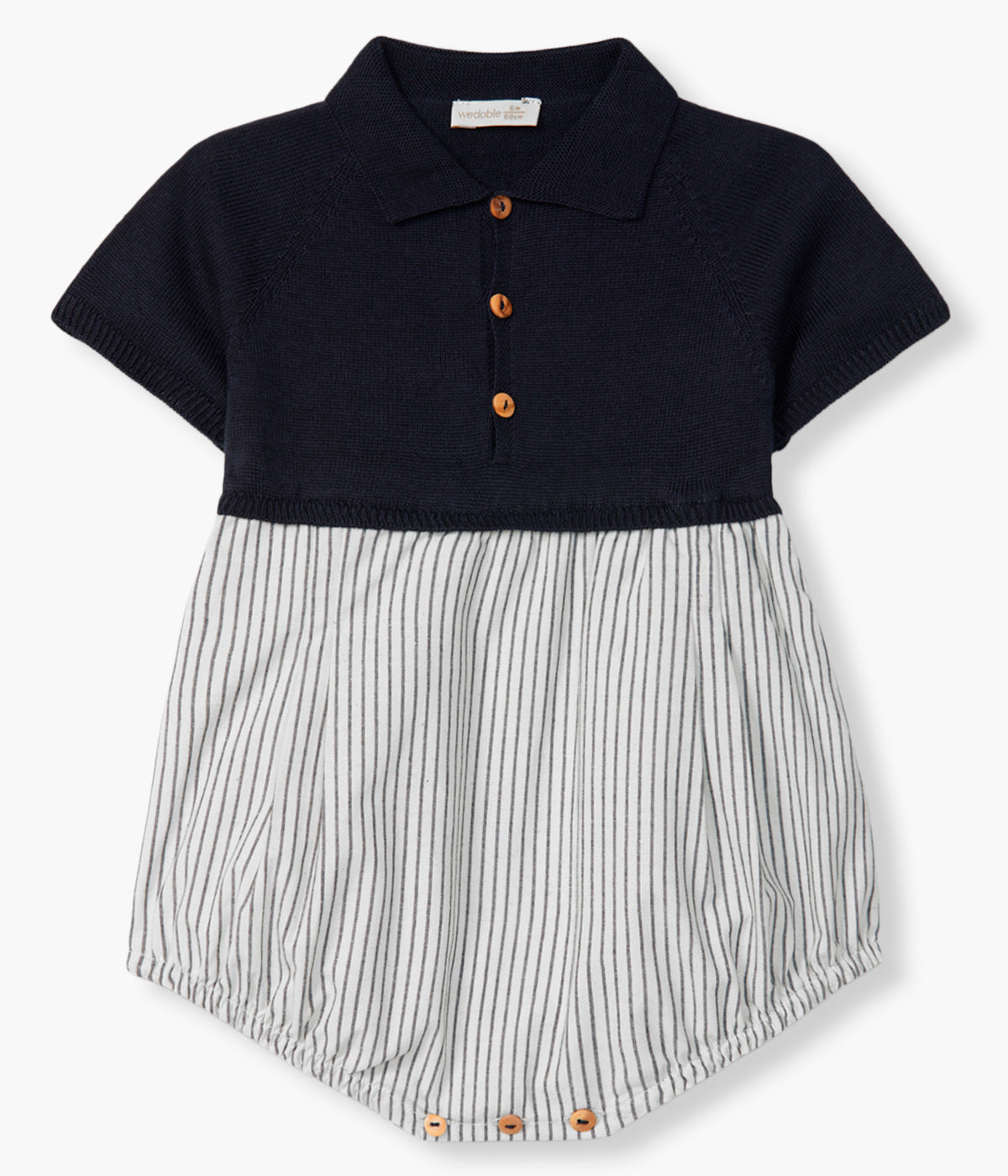 Vista de frente do fofo da Wedoble para bebé menino e recém-nascido. Elegante fofo com parte superior em malha de algodão orgânico azul com gola bico cortada e abertura no peito com botões de madeira. Parte inferior em tecido efeito balão em algodão branco com padrão riscas azuis.