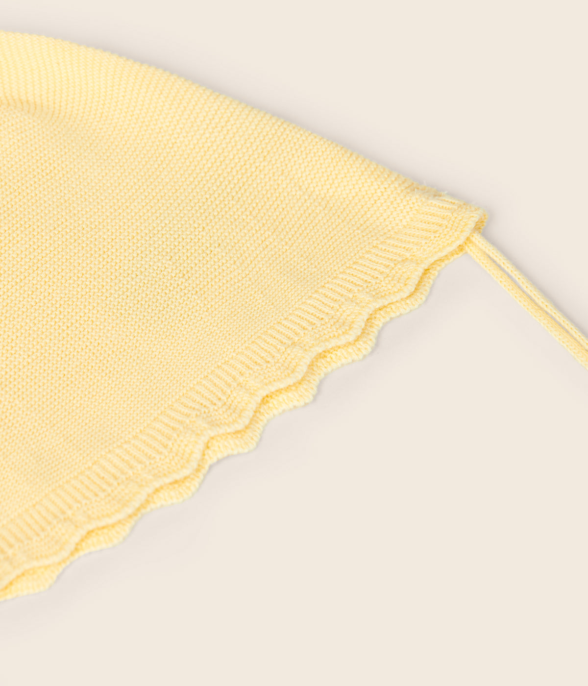 Vista de frente do chapéu em malha de algodão orgânico amarelo sem costuras no interior da Wedoble para bebé e recém-nascido(a). Efeito ondulado a toda a volta. Tiras para atar no queixo.