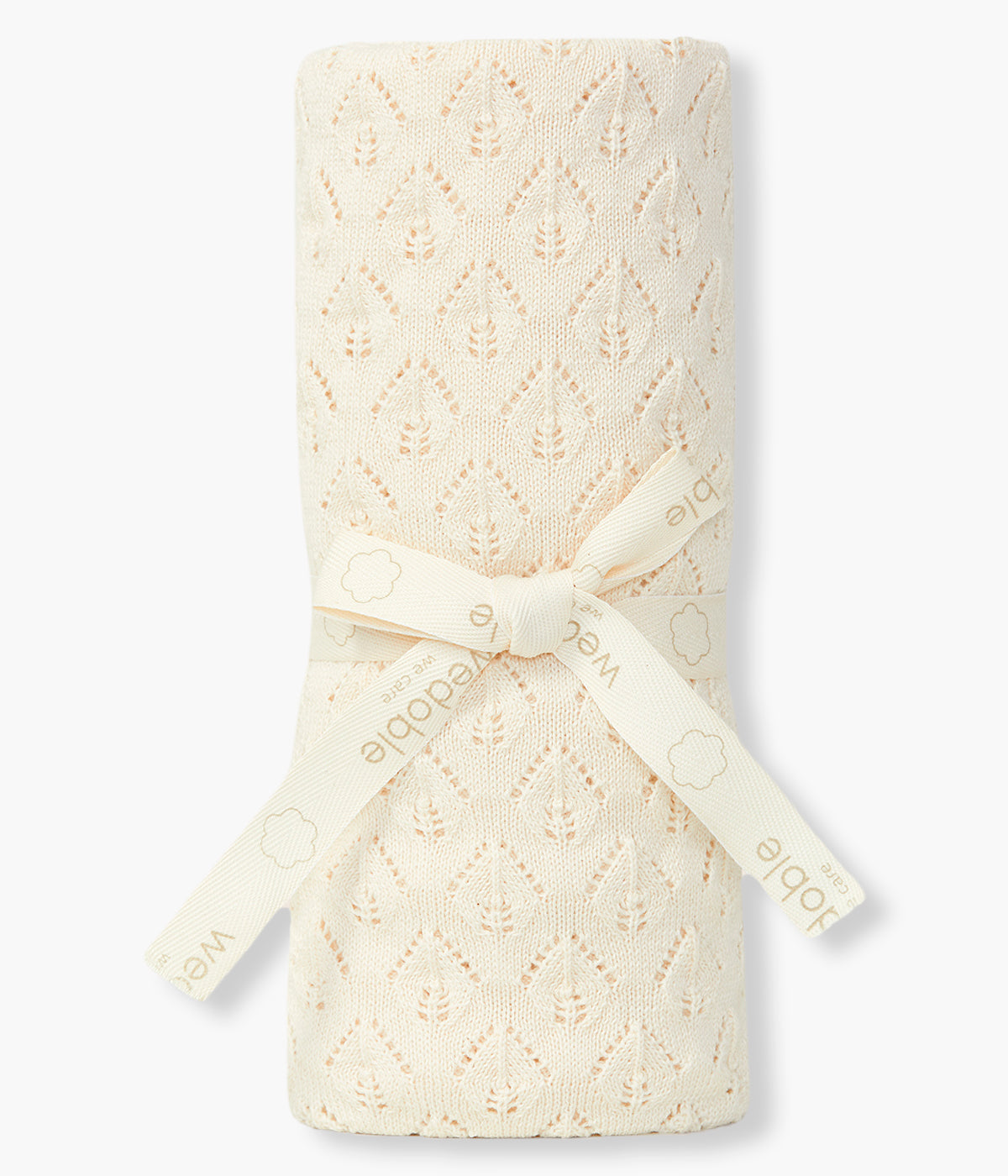 Vista dobrada da manta em malha de algodão orgânico bege da Wedoble para bebé e recém-nascido(a). Delicada manta de formato retangular com detalhes perfurados.