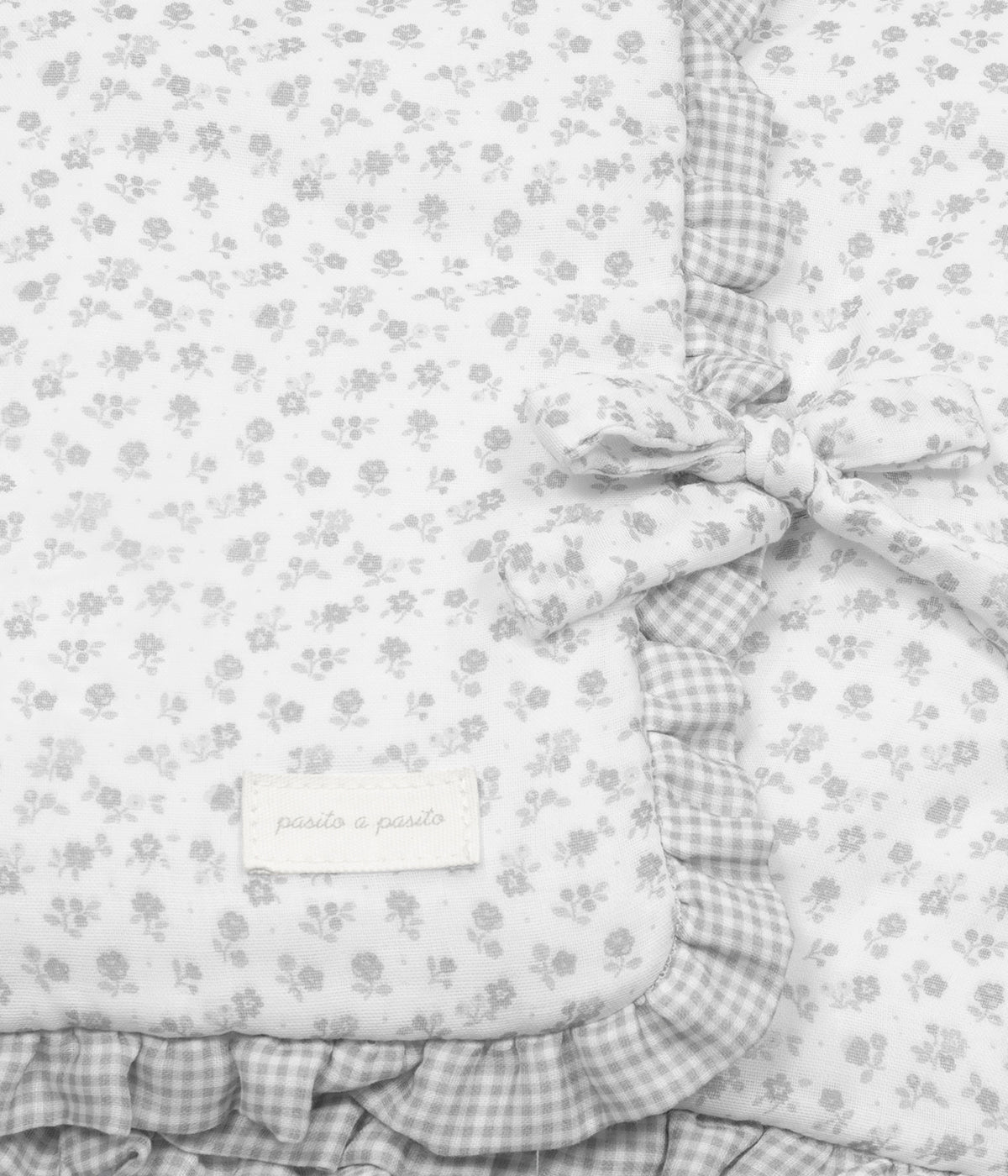 Vista com laço fechado do saco manta Pasito a Pasito Little Bloom Flowers com clássico padrão floral em tons cinza. Feito em musselina de algodão e com um TOG de 2.5, este saco manta é ideal para a pele delicada do(a) recém-nascido(a). Possui um design funcional permitindo ser utilizado como ninho ou como manta de berço, acompanhando o crescimento e as diferentes necessidades do bebé.