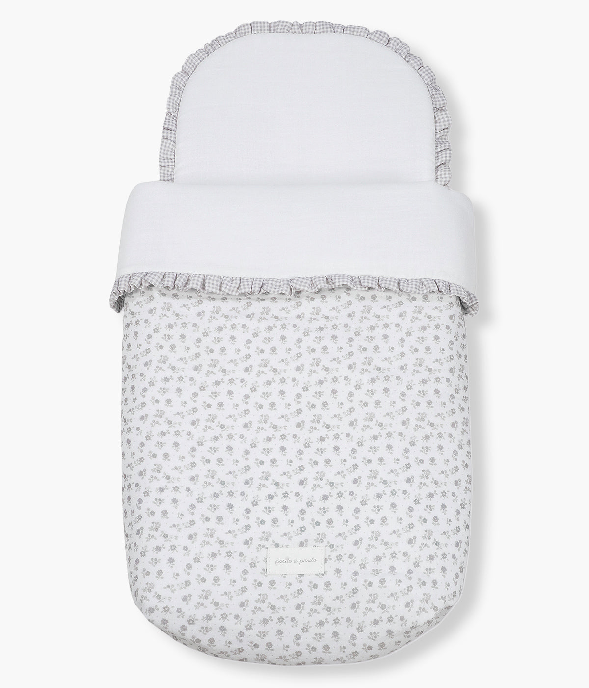 Vista de frente do saco de dormir Little Bloom Flowers da Pasito a Pasito. Delicado saco de dormir para alcofa que envolve a bebé em conforto e suavidade desde os primeiros passeios. Criado com tecido 100% algodão, combina muselina com padrão floral cinza, um interior liso com enchimento removível e colchão interior com tecido 3D para maior ventilação.