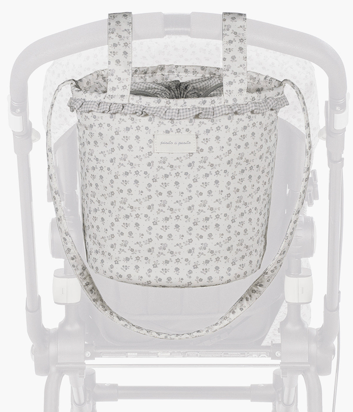 Vista pendurada no carrinho da bolsa Bucket Little Bloom Flowers da Pasito a Pasito. Prática bolsa com exterior em loneta de algodão à prova de água com um clássico padrão floral em tons de cinza. O seu formato tipo balde maximiza o espaço interior, permitindo uma organização prática e um acesso rápido aos essenciais da bebé.