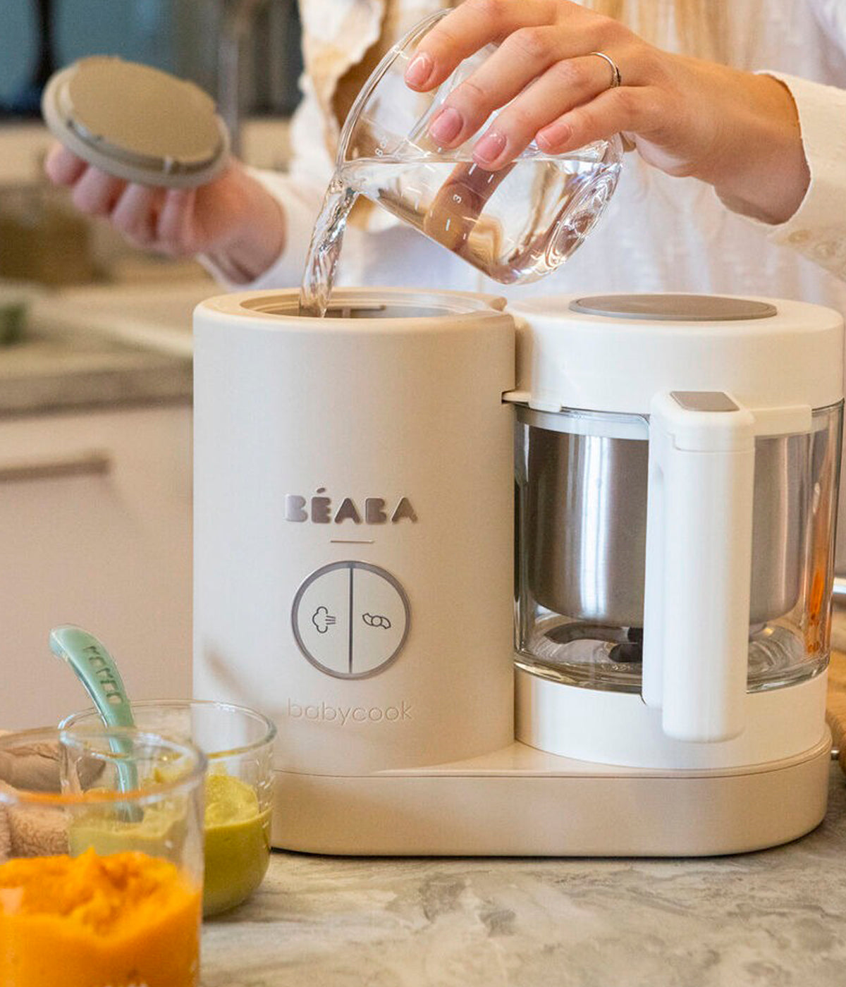 Vista a ser utilizado do robô de Cozinha Babycook Néo da Béaba na cor Clay Earth (bege). Inteligente robô de cozinha premium para bebé 6 em 1 que cozinha a vapor, tritura, descongela, aquece refeições, aquece biberões e esteriliza acessórios.