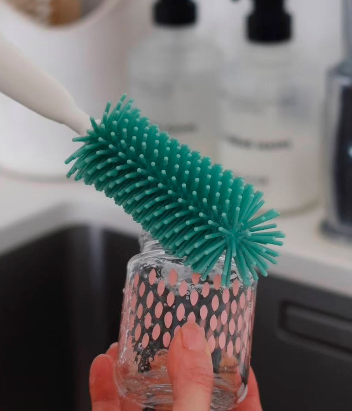 Vista em utilização da escova limpa-biberões em silicone da Béaba na cor verde.