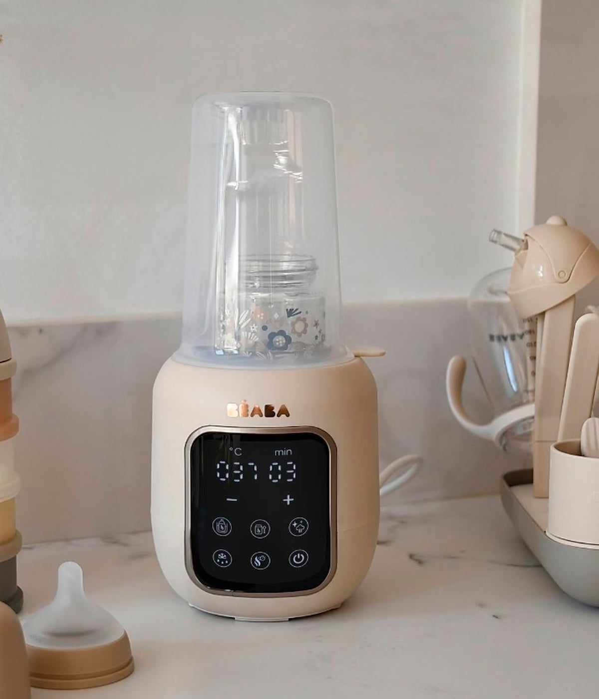 Vista frontal do Aquecedor de biberões Multi Milk da Béaba na cor Clay Earth (bege). Prático aquecedor e esterilizador multifunções com 5 programas integrados que permitem aquecer biberões e boiões, descongelar leite materno e esterilizar acessórios de forma prática, rápida e segura. O ecrã tátil intuitivo e o aquecimento homogéneo tornam a rotina diária mais simples.
