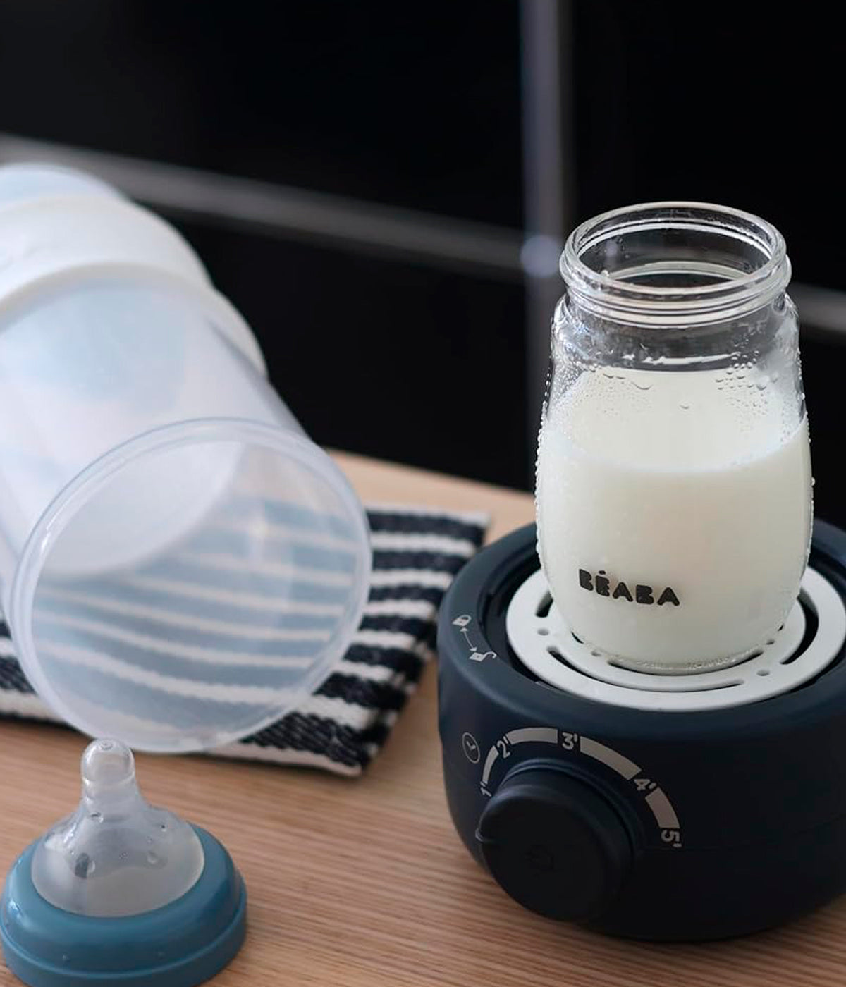 Aquecedor de biberões Babymilk Second da Béaba na cor Night Blue (azul índigo) a aquecer leite para o bebé.