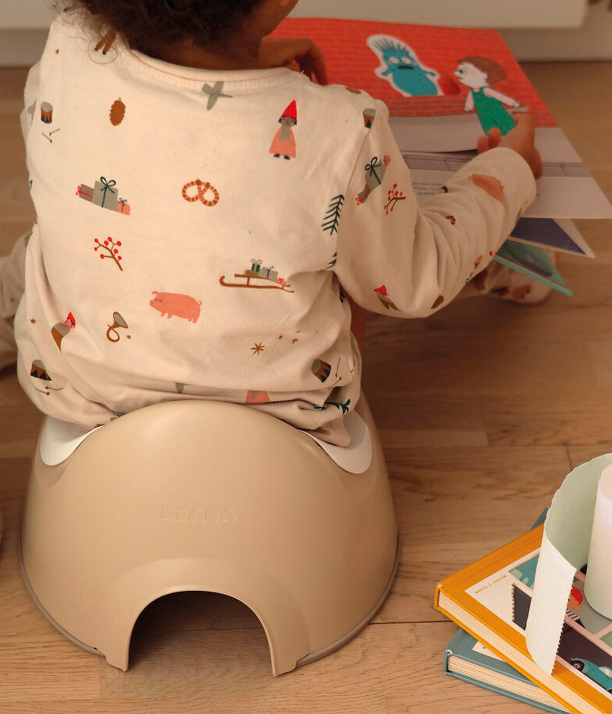 Vista frontal do bacio ergonómico Potty da Béaba na cor Clay Earth (bege) com o bebé a utilizar.