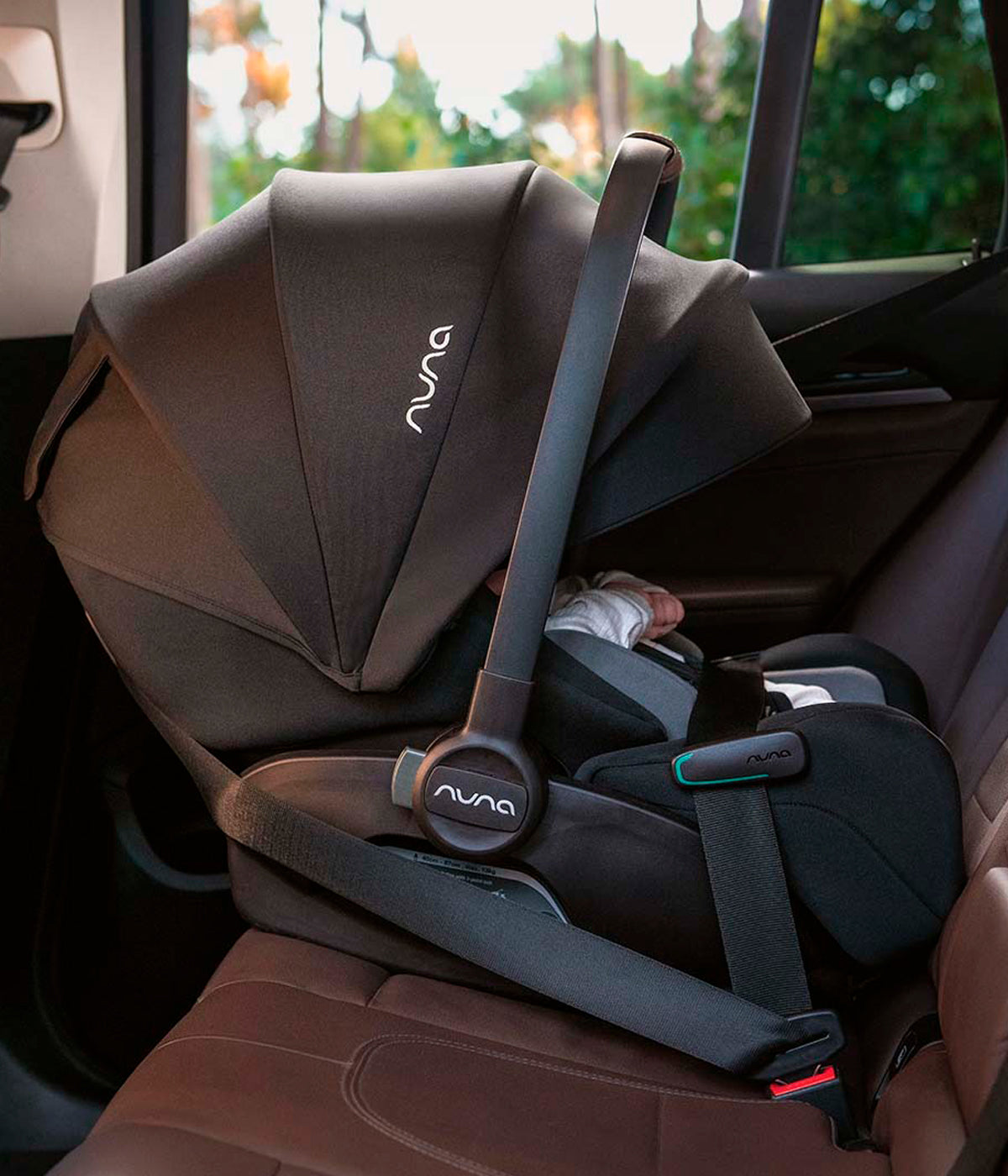 Babycoque para bebé Arra flex da marca Nuna na cor Chestnut instalada no automovel através dos cintos.