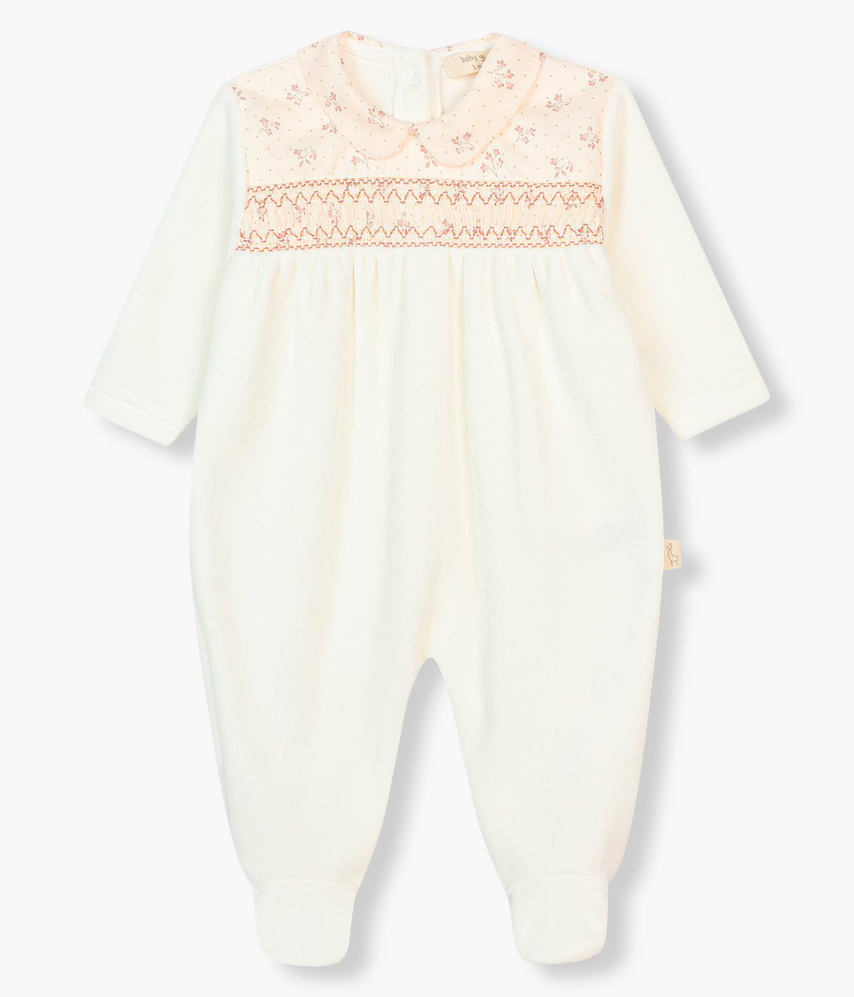 Vista frontal do babygrow em veludo pérola da Baby Gi para bebé menina e recém-nascida. Gola redonda cortada e detalhe no peito rosa com pequenas flores. Abertura nas costas e entrepernas.