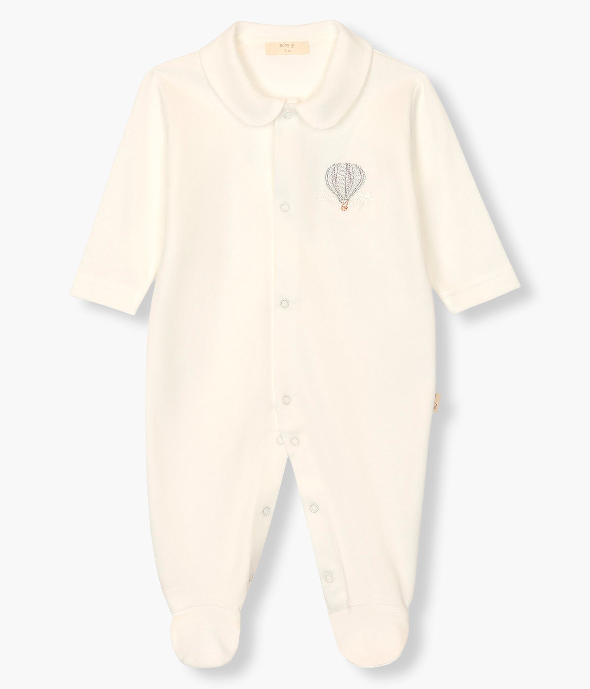 Vista frontal do babygrow em veludo pérola da Baby Gi para bebé e recém-nascido(a). Gola redonda cortada. Balão de ar quente em tons de azul bordado no peito. Abertura com molas de pressão na frente e entrepernas.