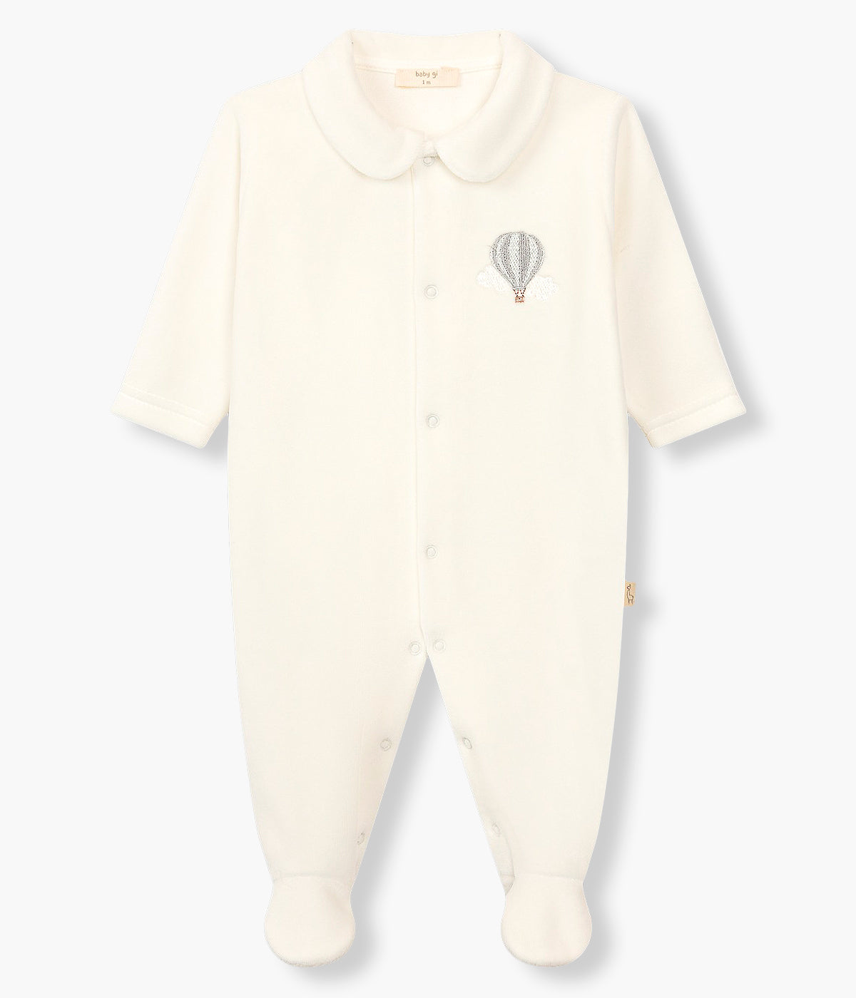 Vista frontal do babygrow em veludo pérola da Baby Gi para bebé e recém-nascido(a). Gola redonda cortada. Balão de ar quente em tons de azul bordado no peito. Abertura com molas de pressão na frente e entrepernas.