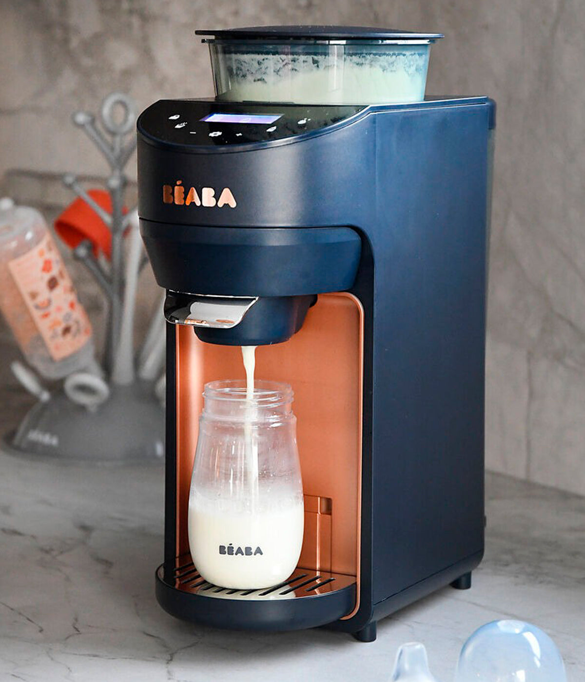 Vista frontal do preparador automático de biberões Milkéo Plus V2 da Béaba na cor Night Blue. Inteligente aparelho que simplifica a preparação das refeições ao dosear automaticamente a fórmula em pó e a água, aquecer, misturar e dispensar diretamente para o biberão em menos de 20 segundos. 