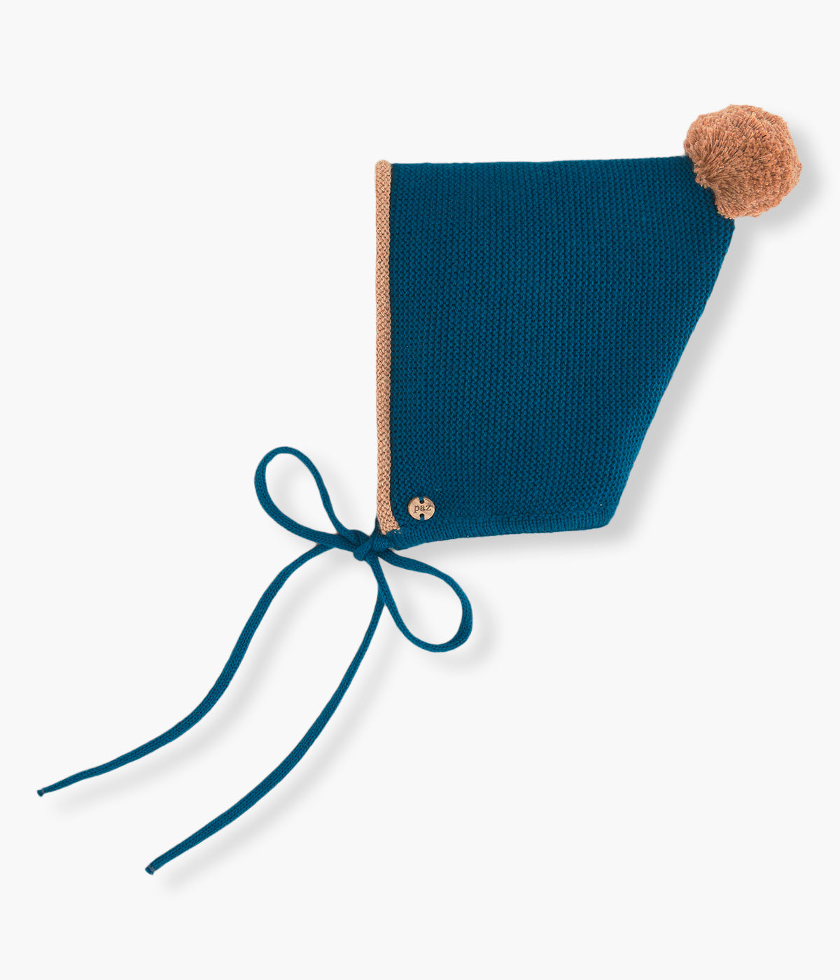 Vista lateral do gorro em malha com algodão da Paz Rodríguez para bebé e recém-nascido(a). Pompom e contorno em bege. Medalha da marca em madeira. Tiras para atar no queixo.