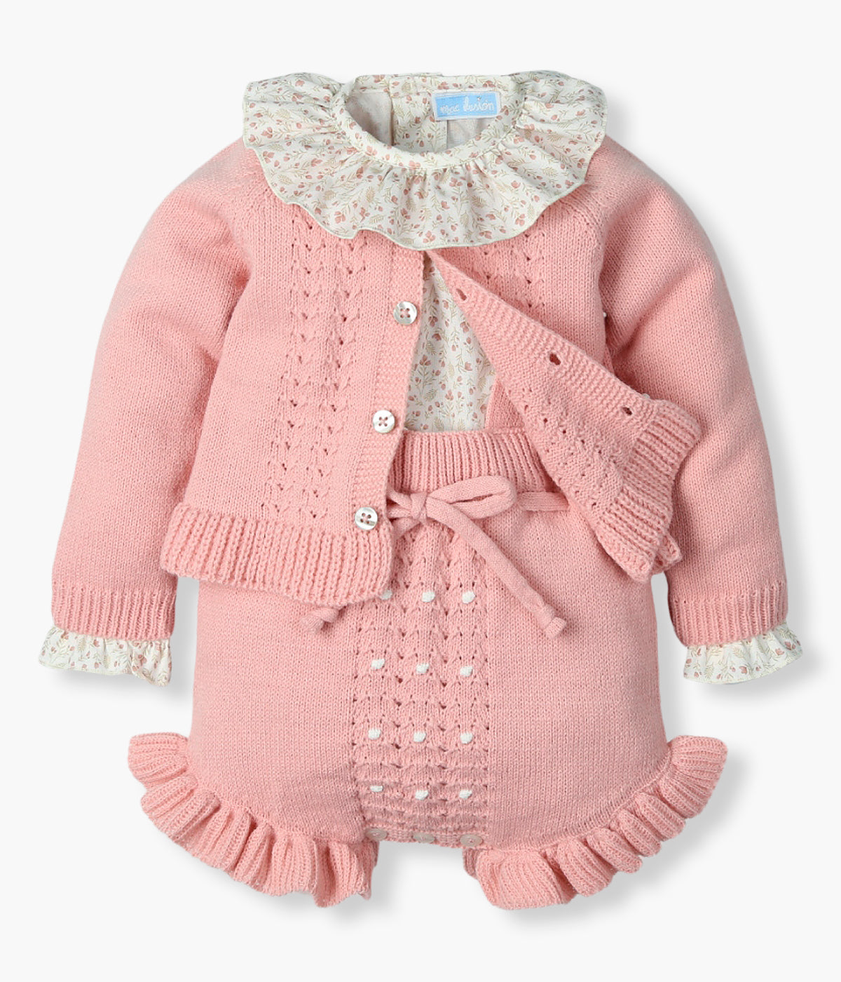 Vista frontal do conjunto de 3pc da Mac Ilusión para bebé menina e recém-nascida. Blusa em algodão pérola com padrão pequenas flores e golha folho. Macacão e casaco em malha rosa com detalhes na malha.