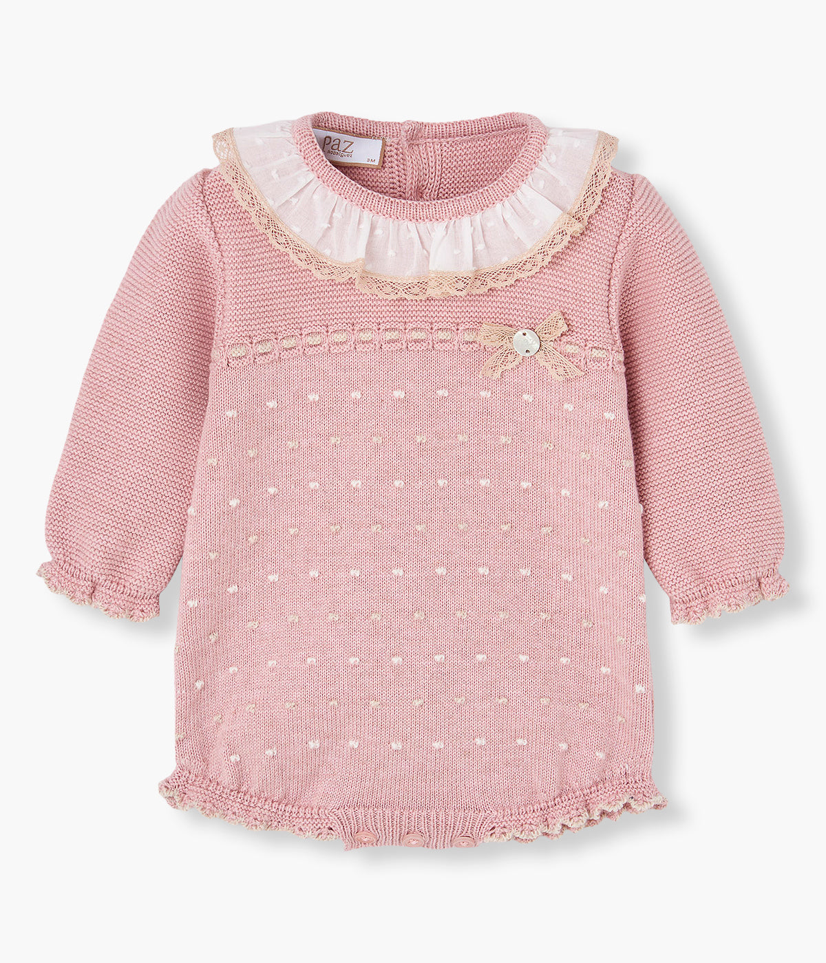 Vista frontal do fofo rosa da Paz Rodríguez para bebé menina e recém-nascida. Gola folho em tecido plumeti branco com rebordo em renda bege, detalhes com relevo em bege e medalha de madrepérola com laço a combinar. Abertura nas costas e entrepernas.