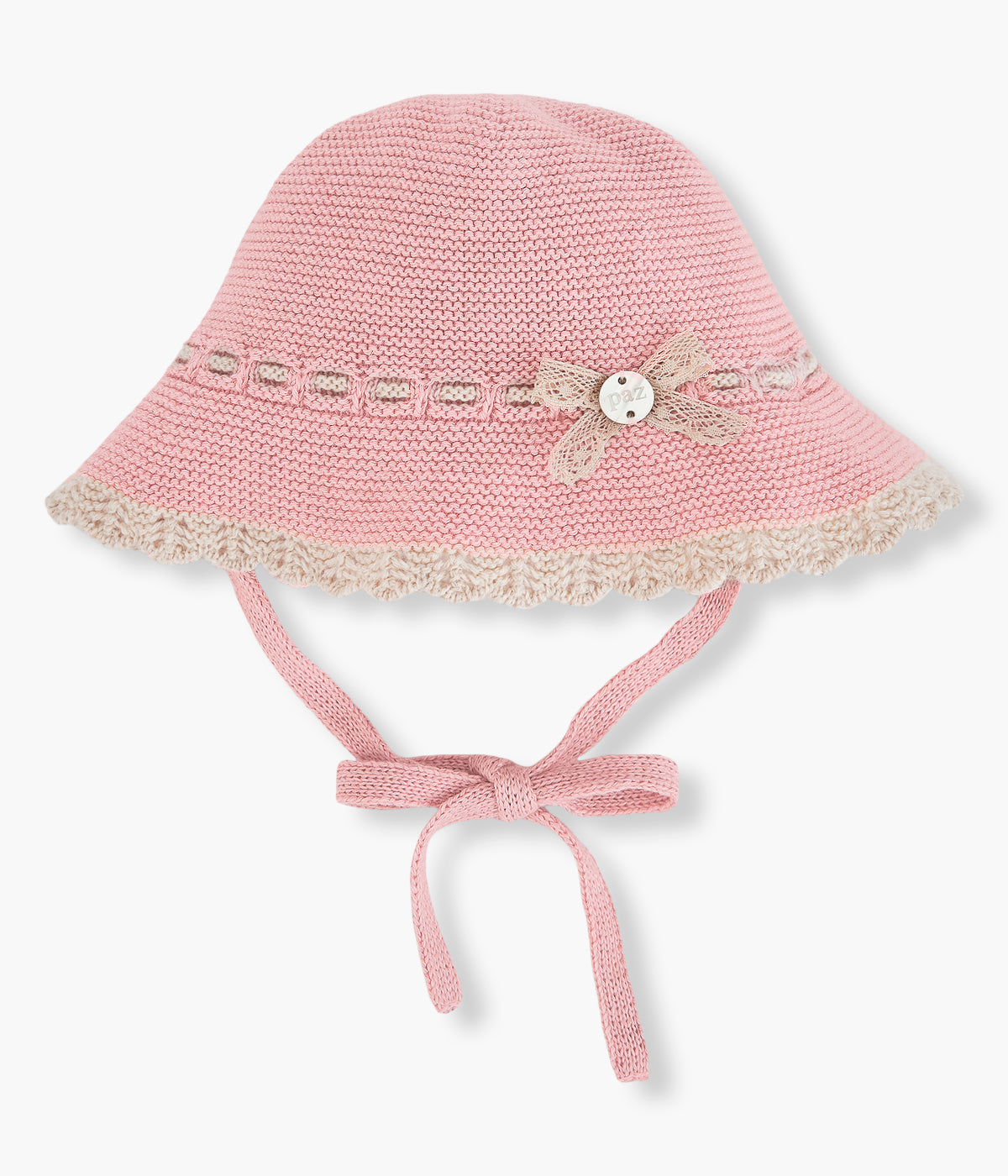 Vista frontal do chapéu em malha de algodão e caxemira rosa da Paz Rodríguez para bebé menina e recém-nascida. Suave chapéu com detalhes em bege, rebordo ondulado e medalha de madrepérola com laço em renda. Tiras para atar no queixo.