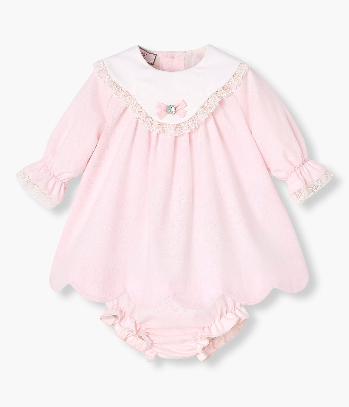 Vista frontal do vestido com tapa fraldas em algodão da Paz Rodríguez para bebé menina e recém-nascida. Peito com detalhe em tecido e medalha de madrepérola com laço. Detalhes em renda no peito e nos punhos. Contorno inferior com efeito ondulado. Tapa fraldas a combinar.