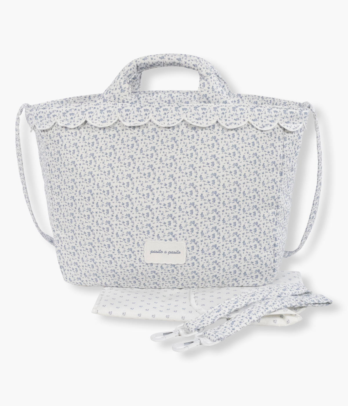 Vista frontal da mala de maternidade Maison Tender Rabbits da Pasito a Pasito. Delicada bolsa que combina o delicado padrão de coelhos com toda a funcionalidade necessária para os passeios com o bebé. Com um exterior em algodão com tratamento resistente à água, possui um interior espaçoso e bem organizado, com bolso térmico, bolso plastificado e vários compartimentos para os essenciais do dia a dia. Inclui um resguardo portátil e pode ser transportada à mão, ao ombro ou facilmente presa ao carrinho de bebé.