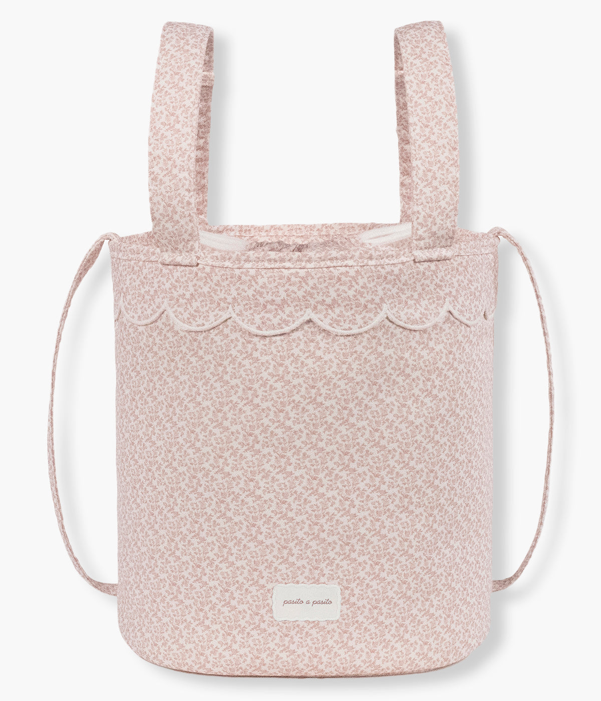 Vista frontal da bolsa bucket Maison Tender da Pasito a Pasito com o padrão flores. Elegante bolsa que combina um formato compacto e funcional com o delicado padrão de flores rosa da coleção. Fabricada em algodão BCI com tratamento resistente à água, possui forro interior em poliéster, fecho superior por cordão ajustável e espaço para transportar os principais essenciais da bebé. Inclui alças adicionais para prender ao carrinho e uma alça comprida para transportar ao ombro.