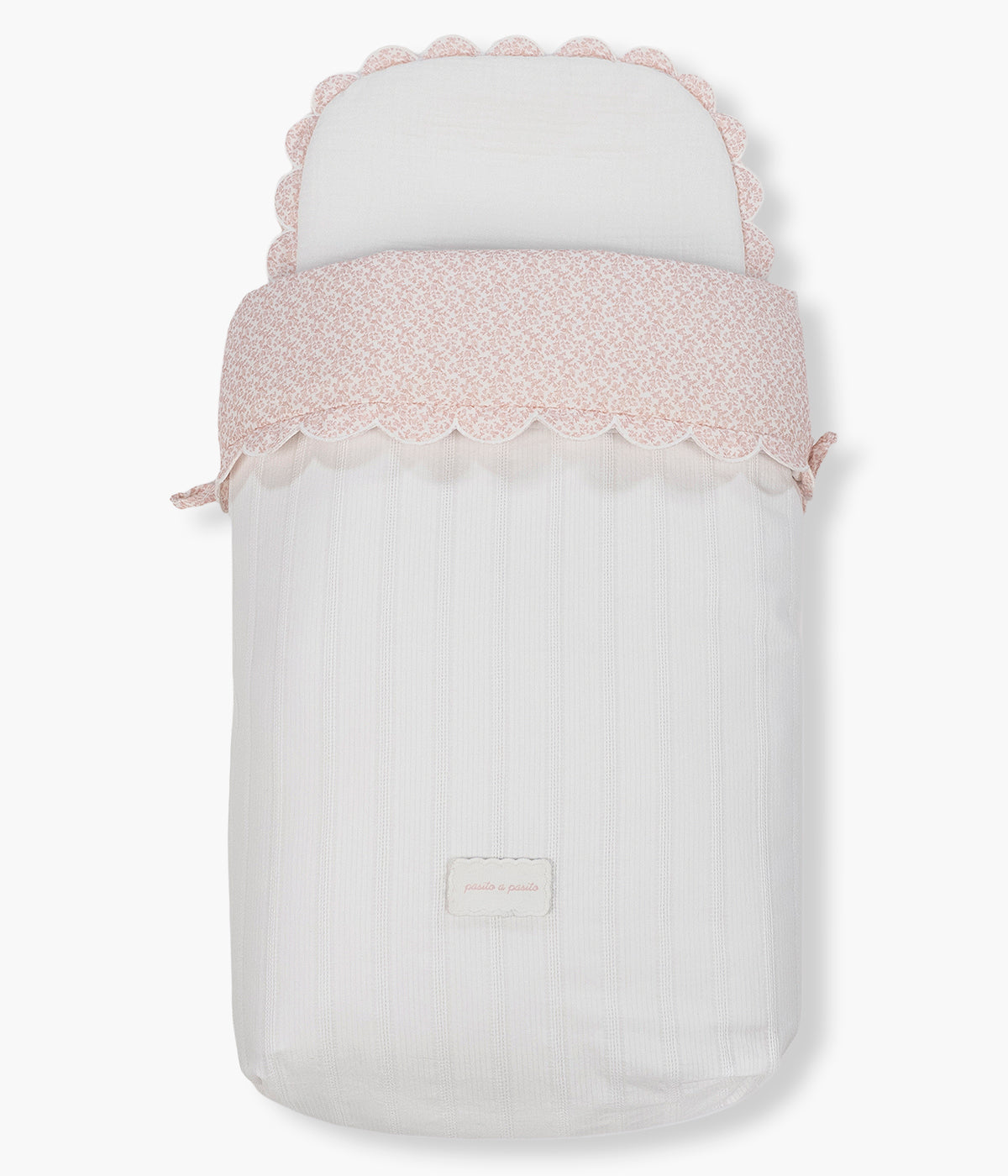 Vista detalhada do saco de dormir Maison Tender da Pasito a Pasito. Elegante saco manta com TOG 2.5 que proporciona um espaço suave, confortável e acolhedor para os primeiros passeios da bebé. Fabricado em 100% algodão, combina um exterior branco com delicada textura de riscas verticais e um interior em musselina de algodão com padrão flores rosa.