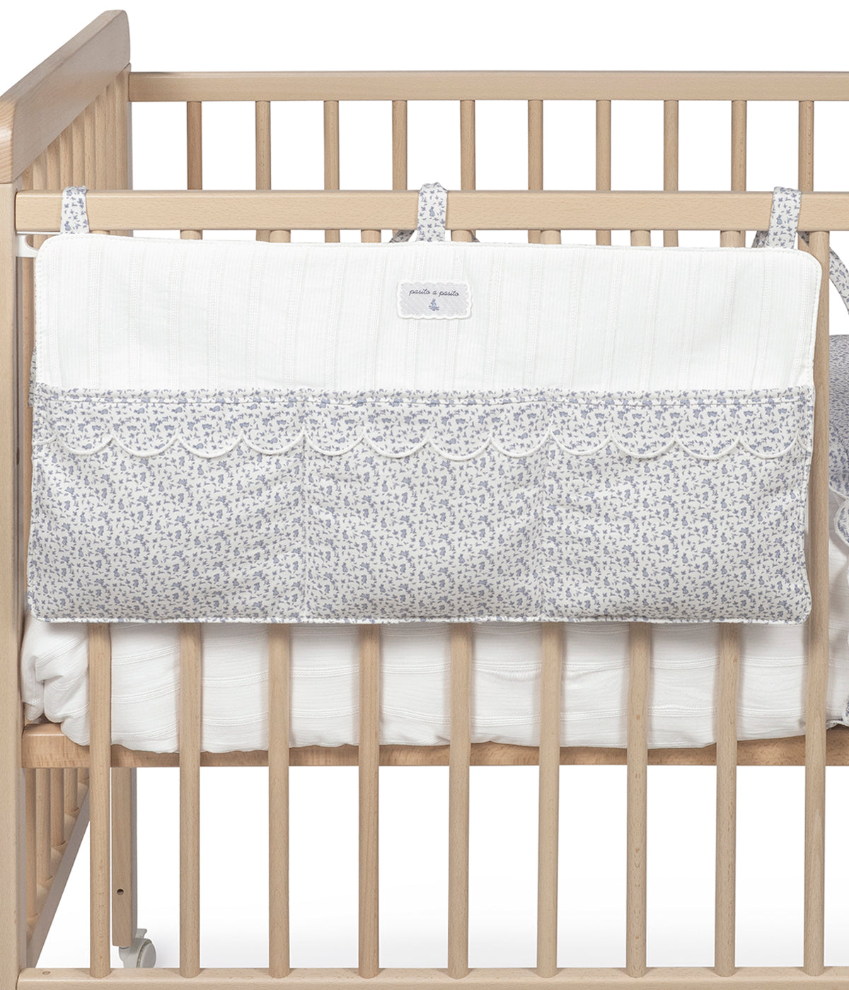 Vista aplicada no berço do organizador de berço Maison Tender da Pasito a Pasito com o padrão coelhos azuis. Perfeito para manter os essenciais do bebé sempre organizados e facilmente acessíveis junto ao berço.