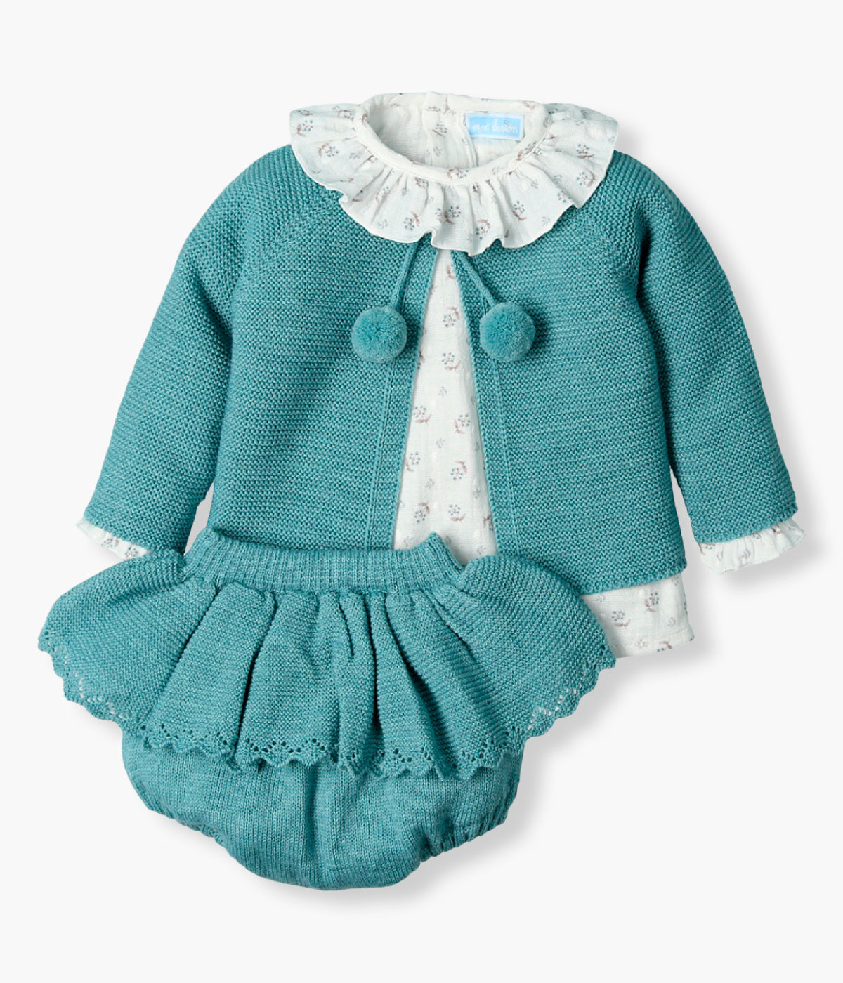 Vista frontal do conjunto de 3pc da Mac Ilusión para bebé menina e recém-nascida. Blusa em algodão plumeti com padrão pequenas flores com gola folho. Fofo com folho e casaco em malha com pompons.