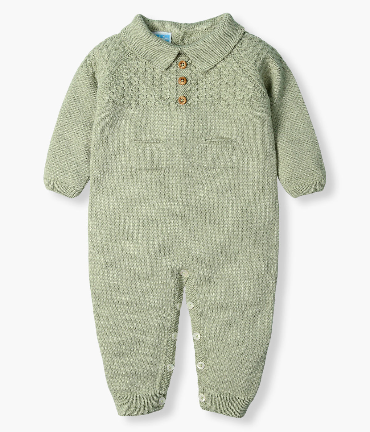 Vista frontal do babygrow em malha da Mac Ilusión para bebé e recém-nascido(a). Gola bico cortada, detalhes na malha , três botões decorativos e dois bolsos decorativos. Sem pés, com abertura nas costas e entrepernas.
