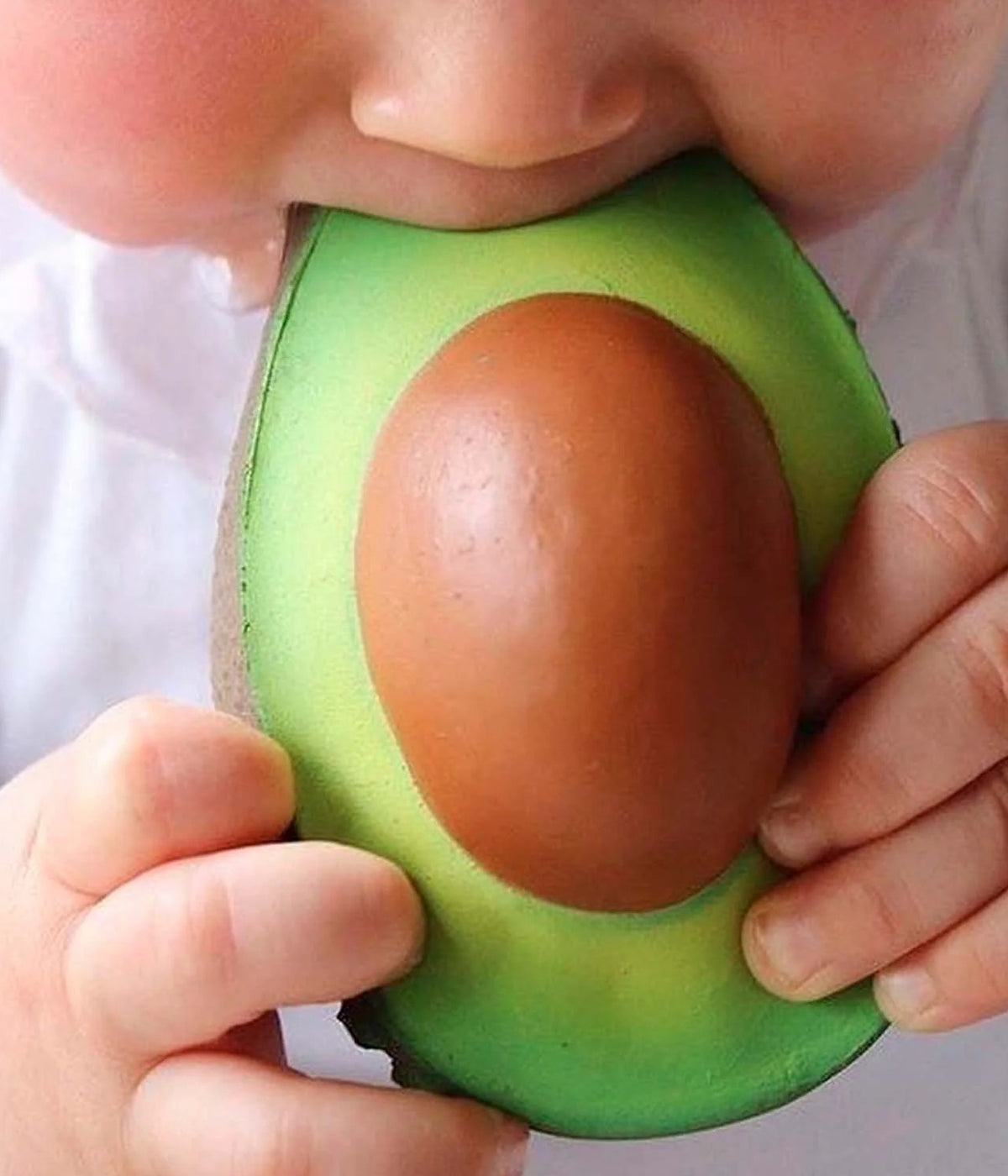 Bebé com mordedor em borracha natural para rnold The Avocado da Oli&Carol na boca.