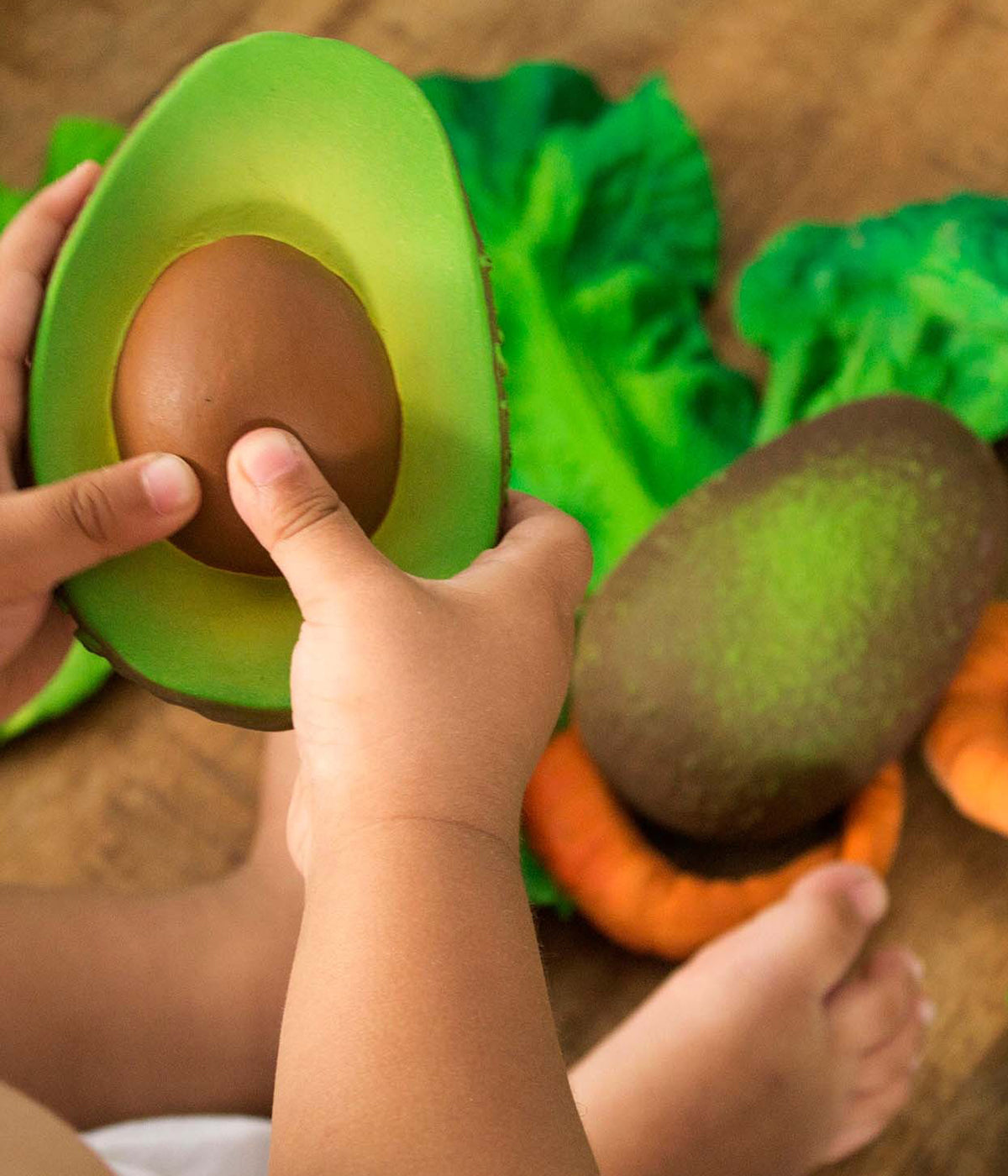 Bebé a segurar o mordedor em borracha natural para bebé Arnold The Avocado da Oli&Carol.