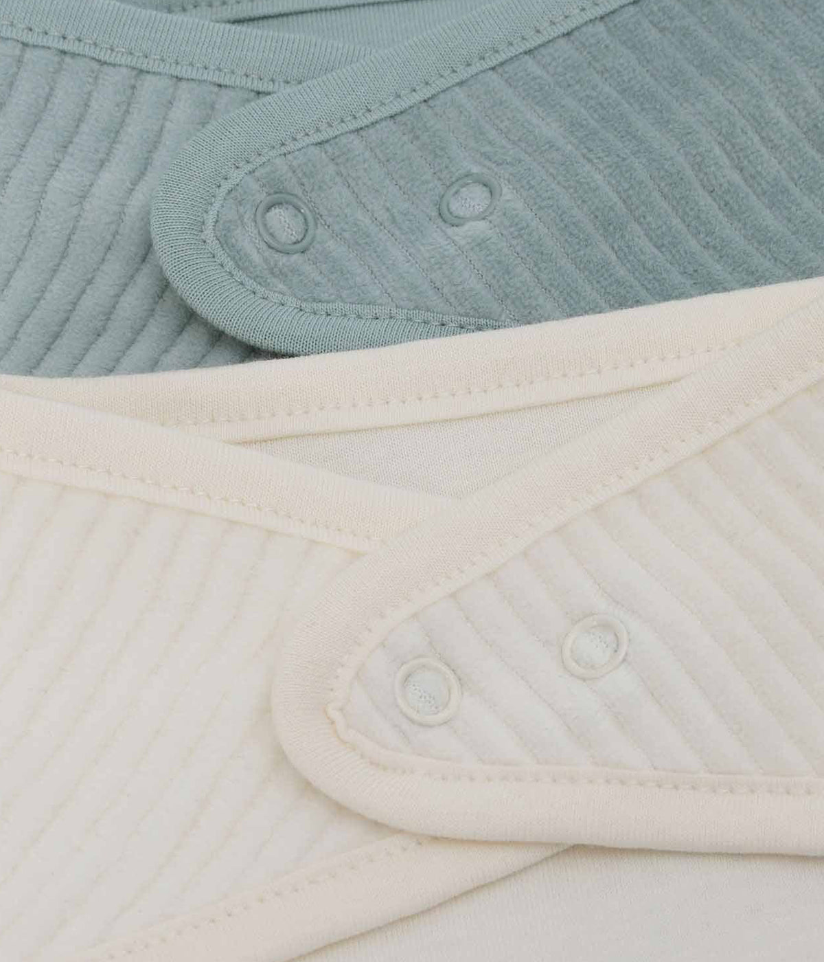 Conjunto de duas babetes em veludo canelado da Jollein para bebé e recém-nascido(a). Suaves babetes, uma pérola e outra azul, perfeitas para manter o bebé limpo enquanto aprende a beber e comer sozinho.