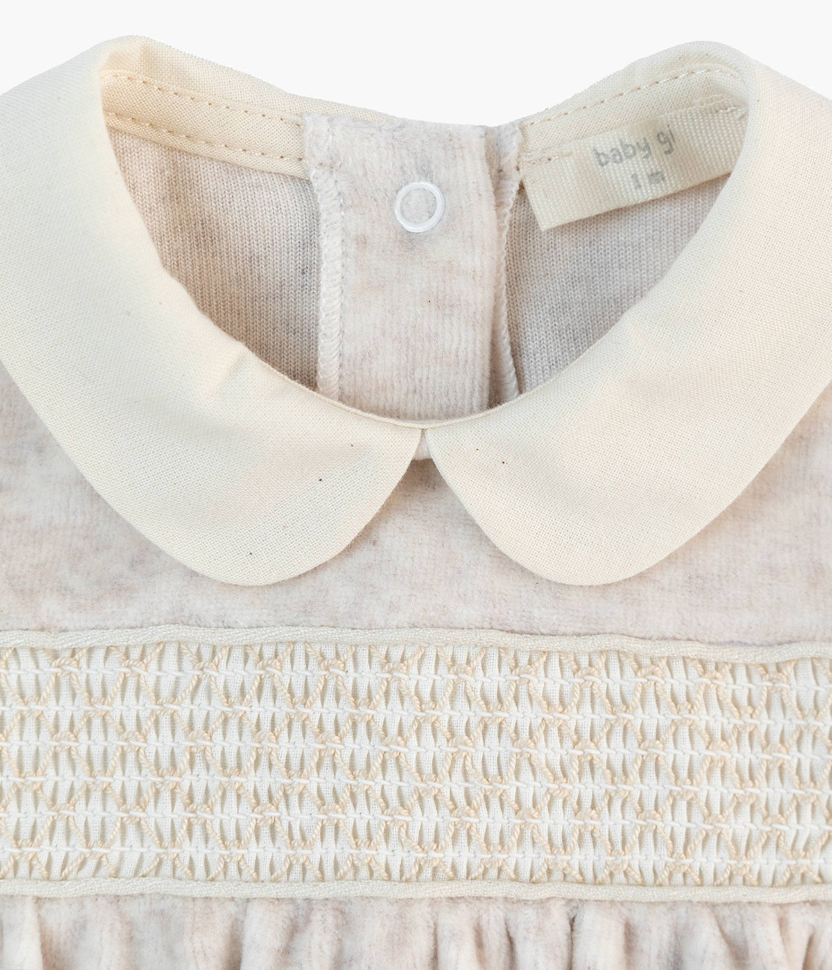 Detalhe da gola do babygrow em veludo bege da Baby Gi para bebé e recém-nascido(a).