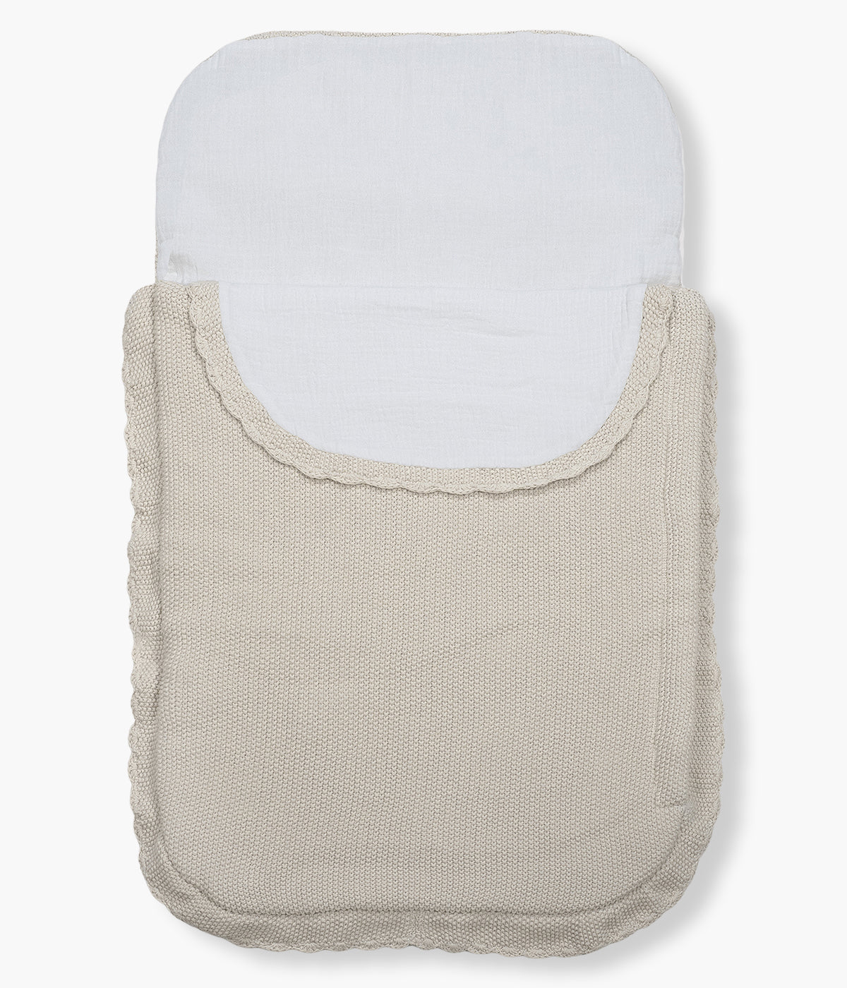 Saco manta em malha de algodão tricot bege da Pasito a Pasito para bebé e recém-nascido(a). Este suave saco manta destaca-se pelo seu ponto de arroz requintado e um elegante acabamento com rebordo ondulado. Possui um design funcional com um interior em tecido musselina branco, permitindo ser utilizado como ninho ou como manta de berço, acompanhando o crescimento e as diferentes necessidades do bebé.