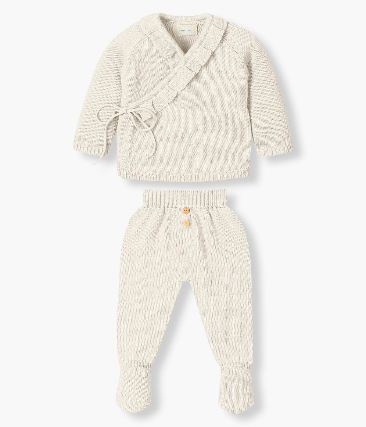 Conjunto em malha de algodão orgânico pérola da Mini Mooi para bebé e recém‑nascido(a), composto por camisola e calças. Camisola de manga comprida abertura trespasse com detalhe de folho na gola e abertura. Calças lisas com pés com botões de madeira decorativos.