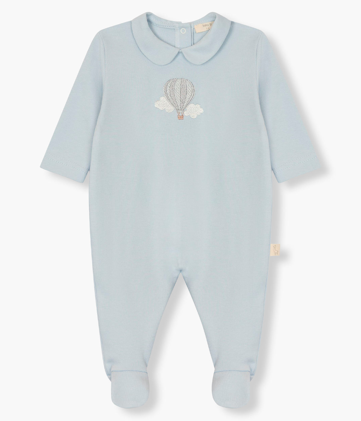 Vista de frente do babygrow em algodão azul da Baby Gi para bebé menino e recém-nascido. Gola redonda cortada e balão de ar quente bordado no peito. Abertura com molas de pressão nas costas e entrepernas.