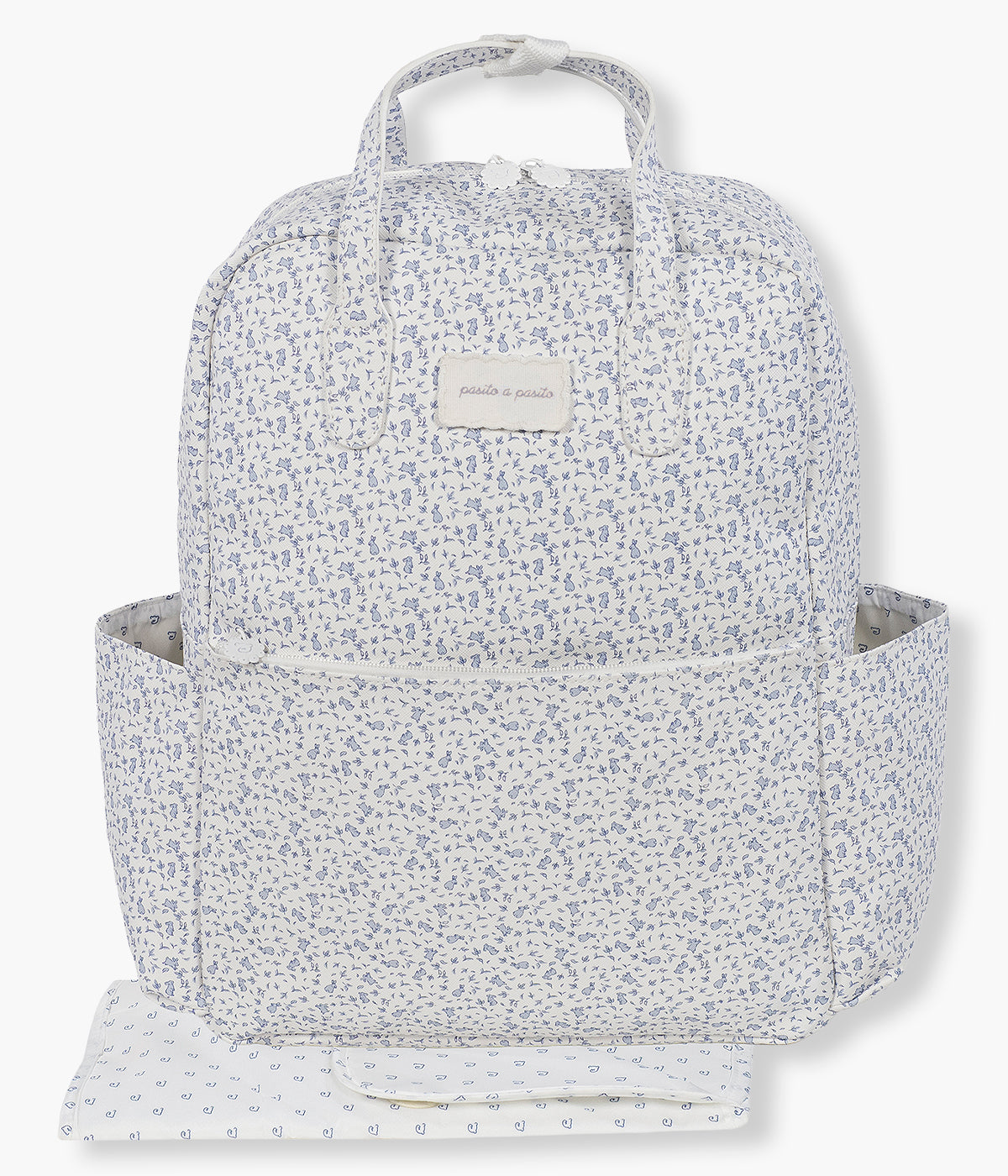 Vista frontal da mochila de maternidade Maison Tender Rabbits da Pasito a Pasito. Fabricada em pele vegana com tratamento resistente à água, esta mochila de padrão coelhos azul em fundo branco oferece um interior espaçoso e bem organizado, com bolso térmico para biberão, bolso plastificado para roupa húmida e vários compartimentos para manter todos os essenciais facilmente acessíveis. Inclui ainda um resguardo portátil.